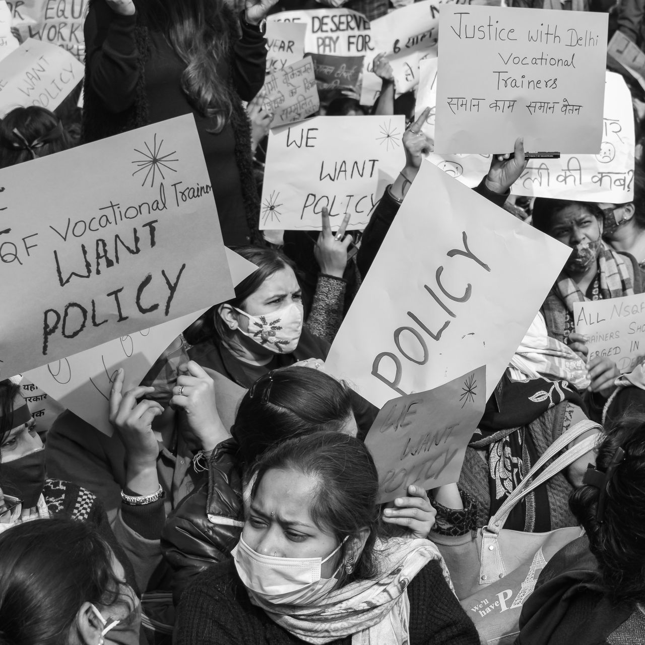 about-bg Black and white image of a protest with signs demanding policy changes for vocational trainers.